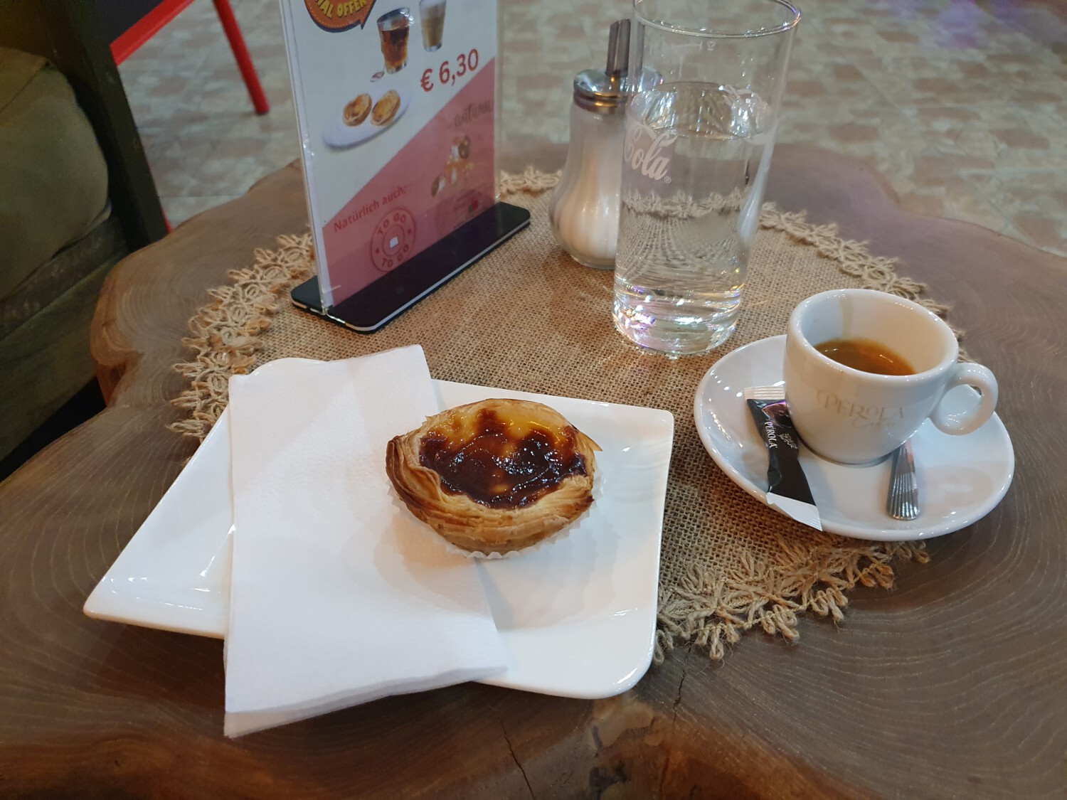 Portuguese pastéis de nata served with espresso and water, in a traditional café setting.